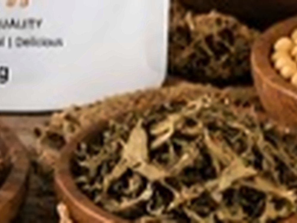 Bowl of dried leafy greens beside African Farm & Gardens packaging on a wooden surface